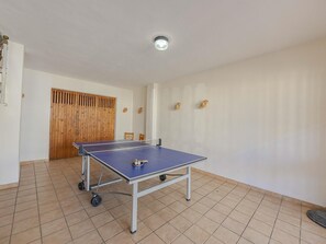 A room with a ping pong table, a wooden door, and a ceiling light fixture. - Laia House: a semi-detached house for 6 in Can Picafort | 3 bedrooms (Can Picafort)