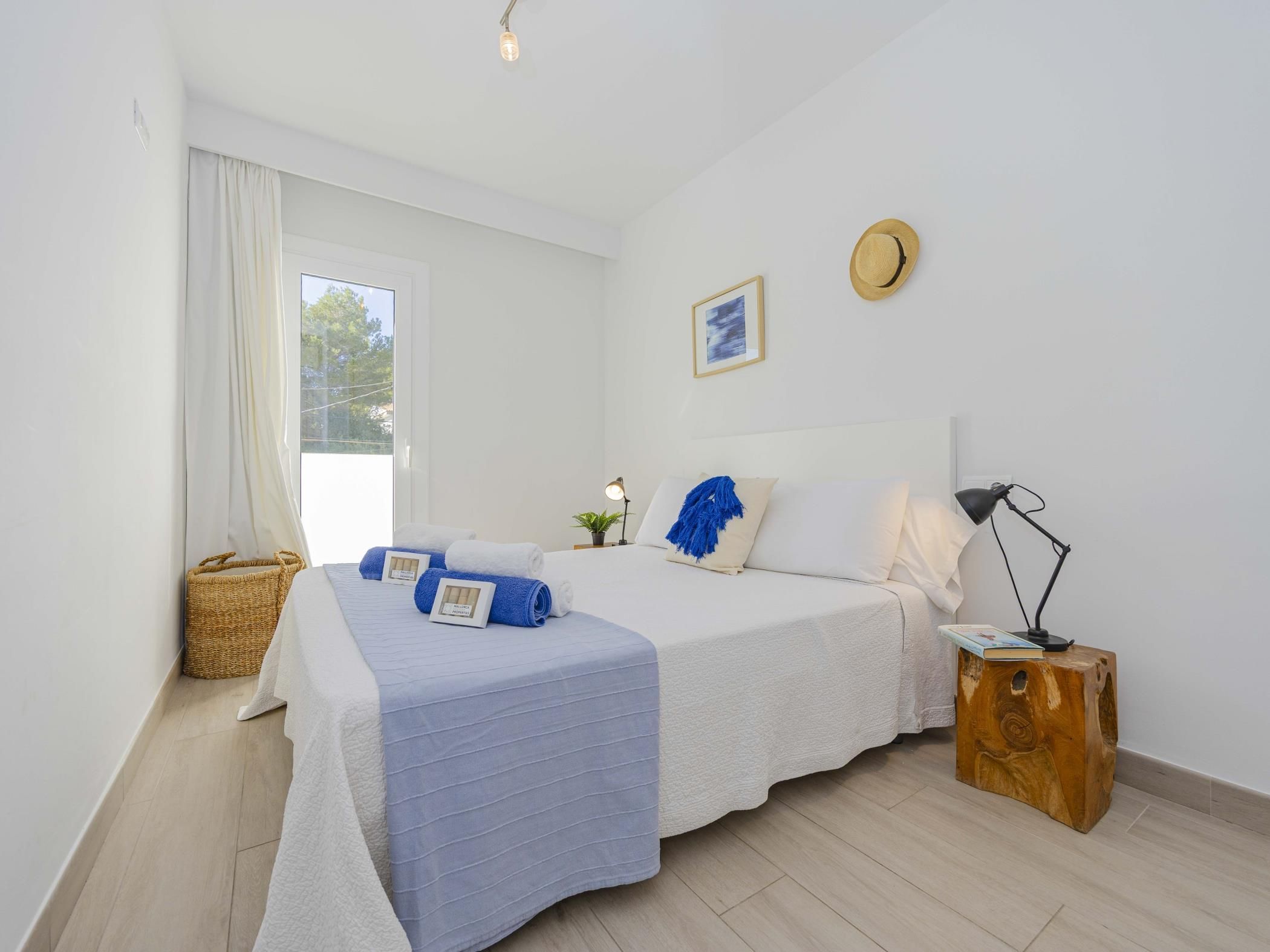 A bedroom with a bed, bedside table, lamp, and a window with curtains.