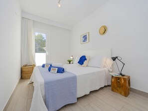 Une chambre à coucher avec un lit, une table de chevet, une lampe et une fenêtre avec des rideaux.