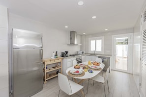 Enjoy cooking in this well-equipped kitchen with a refrigerator, oven, and microwave. The dining area features a table and chairs, with a window offering a view.