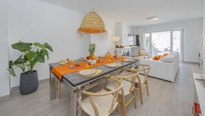 Een moderne eethoek met een lange tafel, stoelen en een hangende lamp.