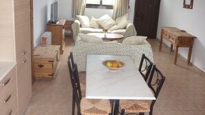 Un espacio habitable compacto con comedor, sofá, televisor y ventana con cortinas.