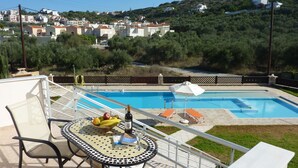 Un área de piscina con una mesa, sillas y un frutero.