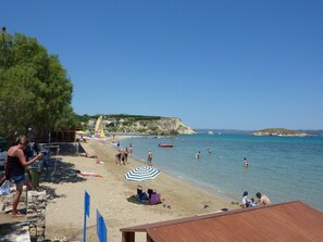 A beach with clear skies, people swimming, and a sandy shore. - Apartment with shared pool only 400 meters from the beach (Almyrida)