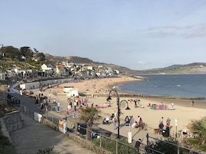 Un pueblo costero con playa, paseo marítimo y casas a lo largo de la orilla.