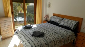 A bedroom with a bed, a wooden dresser, a nightstand, and a window with curtains. - Modern Ground Floor Apartment, Minutes walk from the Arenal beach (Platja de L'arenal)
