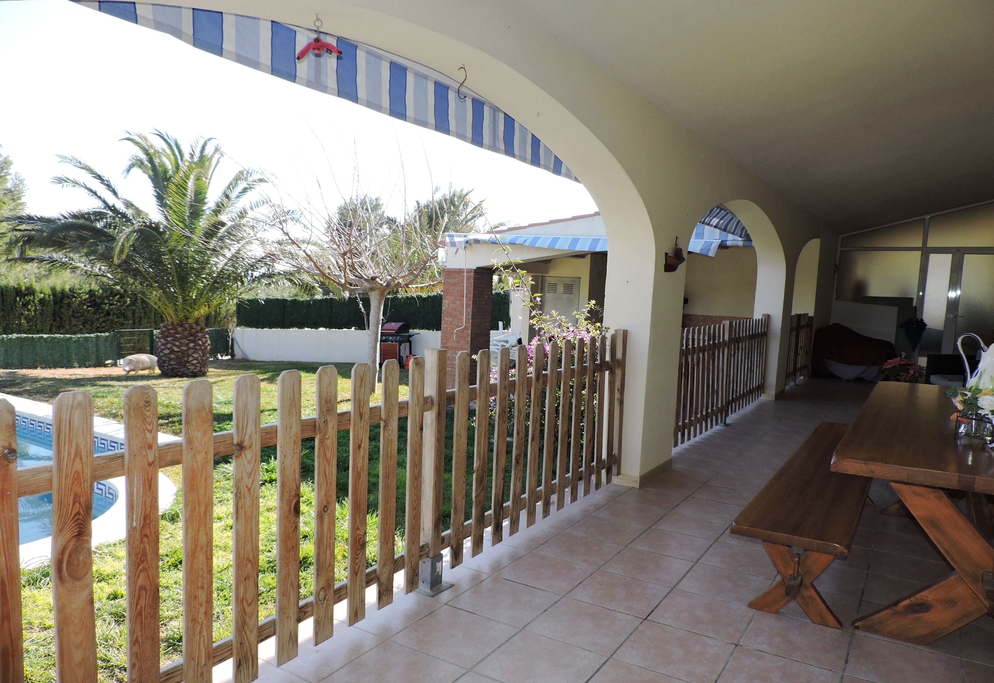 Un patio couvert, agrémenté d’une clôture en bois, d’une piscine et d’une table à manger.