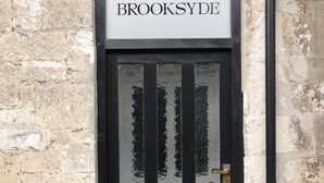 Eine schwarze Tür mit der Aufschrift "BROOKSYDE" darüber, in eine Steinmauer eingelassen.
