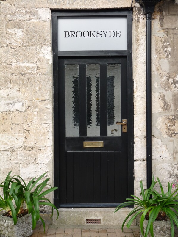 Una puerta negra con el nombre "BROOKSYDE" sobre ella, en una pared de piedra.