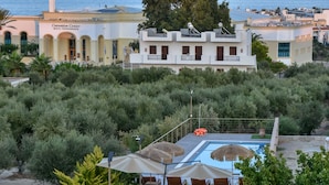 Hotel med swimmingpool, udendørs siddepladser og havudsigt.