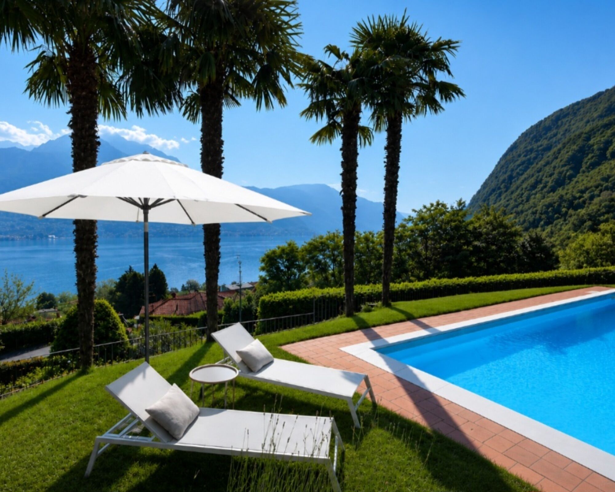 Un espace aménagé au bord de la piscine, avec des chaises longues et une table, entouré de palmiers et offrant une vue sur la mer.