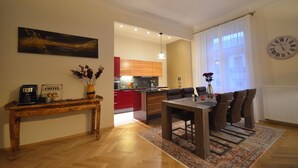 Un salon moderne avec une table basse en bois, une table à manger avec des chaises, un canapé et, au fond, une cuisine.