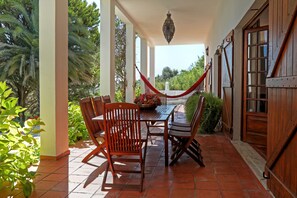 A covered patio with a table and chairs, a hammock, and a view of greenery. - FIFTH WITH PRIVATE POOL AND COURT TENNIS A 30 LISBON M (Vale do Paraíso)