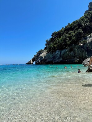 Une mer d’un bleu turquoise limpide, bordée de falaises rocheuses et d’une végétation clairsemée.