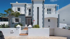 Een modern huis met twee verdiepingen, een witte gevel, een balkon en een garage.