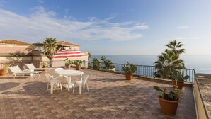 A terrace with a table and chairs, potted plants, and a view of the sea. - House with Big Terrace in Seaside, Syracuse - Ortigia (Siracusa)