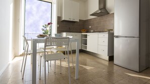 A modern kitchen with white cabinetry, a stainless steel refrigerator, and a window overlooking a balcony. - House with Big Terrace in Seaside, Syracuse - Ortigia (Siracusa)