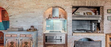 A kitchen with a brick wall, a built-in oven, and a wooden cabinet with drawers.