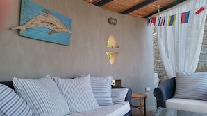 A cozy room with a sofa and chairs, a wall-mounted light fixture, and a decorative wall piece.