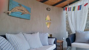 A cozy room with a sofa and chairs, a wall-mounted light fixture, and a decorative wall piece. - Villa Scorpio, Seafront Luxury & Infinity Pool (LAVRIO)