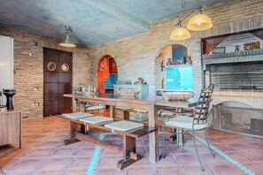 A rustic kitchen with a brick wall, wooden bar, and a built-in oven. - Villa Scorpio, Seafront Luxury & Infinity Pool (LAVRIO)