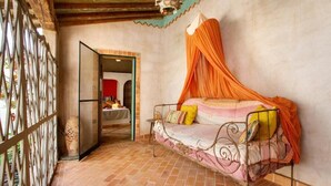 Una habitación con cama, ventana con vistas y puerta que da a otra estancia.