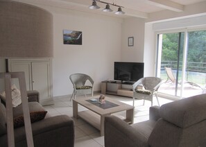 Relax in this stylish living room with a flat-screen TV, comfortable sofa, and wicker chairs.