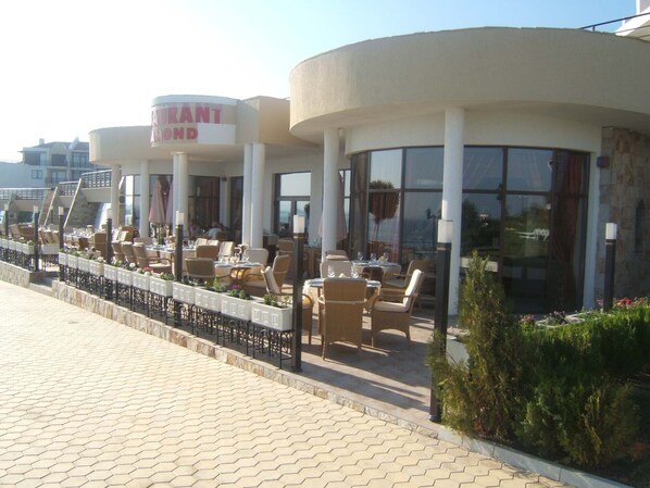A waterfront restaurant with outdoor seating, large windows, and a sign reading "Restaurant".