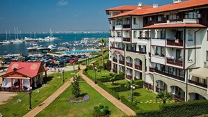 A hotel with multiple balconies, a marina with boats, and a well-maintained garden.