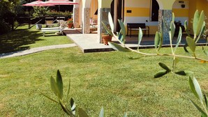 A two-story building with a yellow facade, a balcony with ornate metal railings, and a covered patio area with a red umbrella. - Levanto / Cinque Terre , garden, barbecue, wi fi free, parking, nature, relax (Sesta Godano)