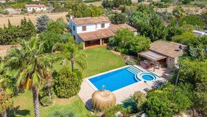 A house with a swimming pool, surrounded by lush greenery and mountains in the background.