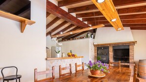 A dining area with a wooden table, chairs, a potted plant, and a fireplace.