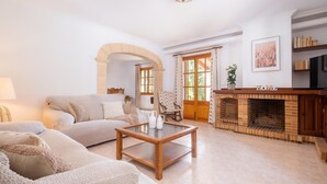 A living room with a sofa, a coffee table, a fireplace, and a door leading to another room.