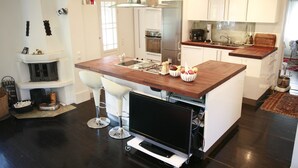 Uma cozinha moderna com ilha central, armários brancos e eletrodomésticos de aço inoxidável.