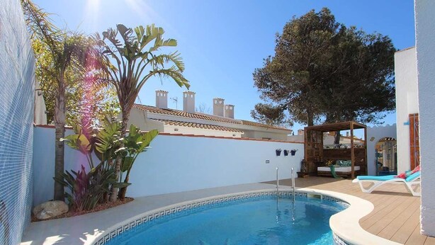 A swimming pool with a tiled edge, surrounded by plants and a wooden deck. - CASA MARINERA,Ideal house for your holidays near the sea, free wifi, optional air conditioning, private pool, pets allowed, dog’s beach (Delta de l'ebre)