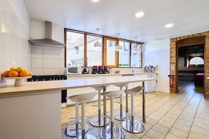 Een moderne keuken met een centraal kookeiland, barstoelen, een magnetron en een fornuis.