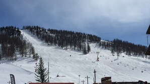 Une piste de ski enneigée, avec un télésiège et des arbres.