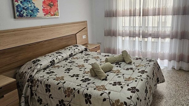 A bedroom with a bed, a headboard, a painting, a window with curtains, and a wall-mounted air conditioner. - TOWNHOUSE WITH PATIOS, BBQ, FREE WIFI AND PARKING AT 5 'ON FOOT OF THE BEACH (Nerja)