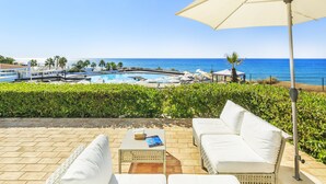 A poolside area with a white outdoor sofa, a table with a book, and an umbrella. - This is Sea View !!! (Almancil)
