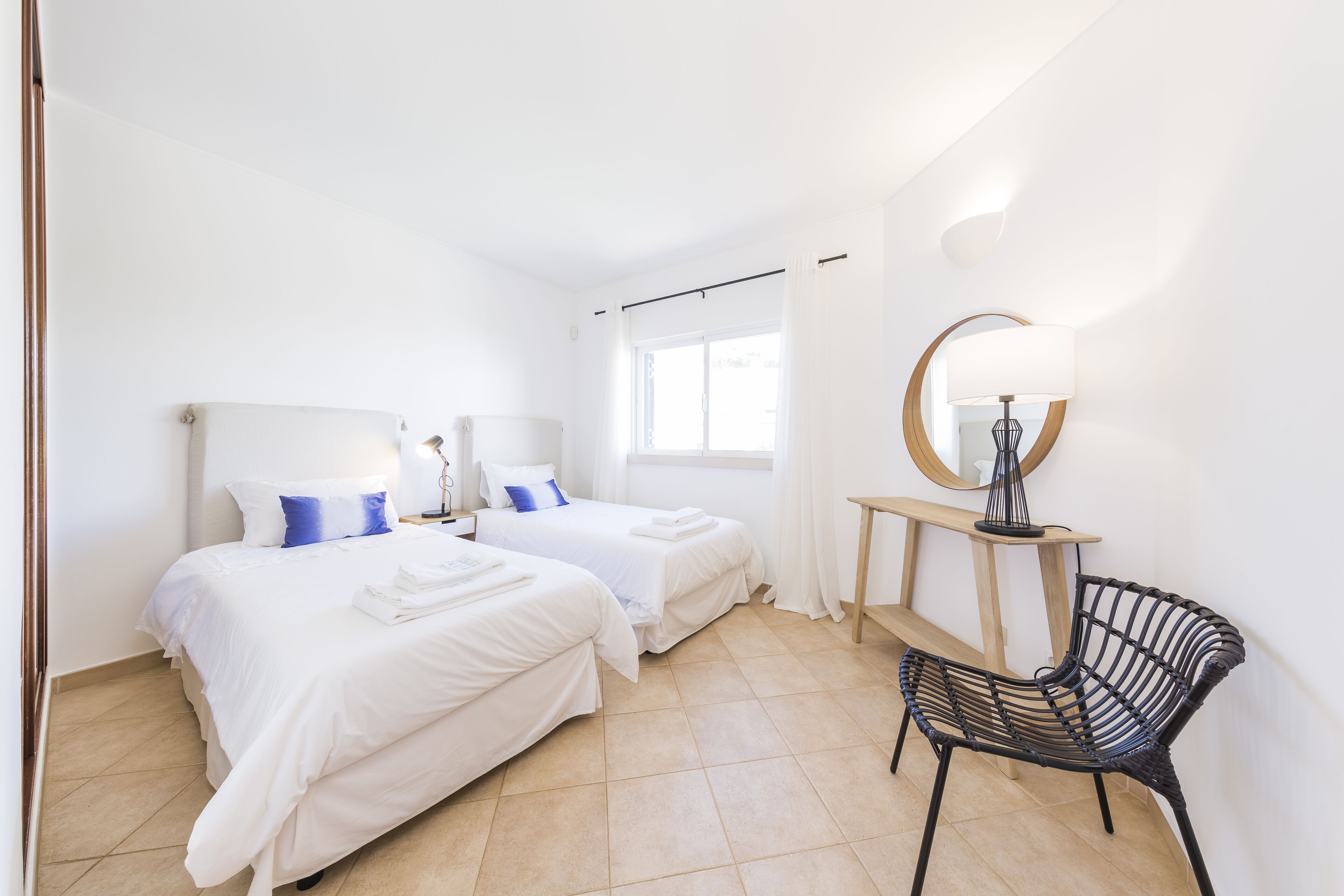 Camera d'albergo con due letti, una sedia, un tavolo e una finestra con tende.