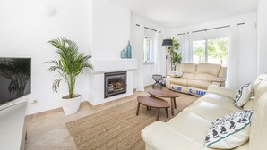 A living room with a fireplace, a sofa, a TV, and a large window. - This is Sea View !!! (Almancil)