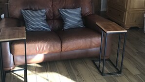 Une pièce avec un canapé en cuir marron, une armoire en bois et un lit avec une literie blanche.
