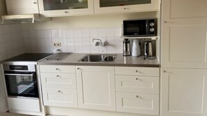 A kitchen with white cabinets, a microwave, a coffee maker, and an oven.