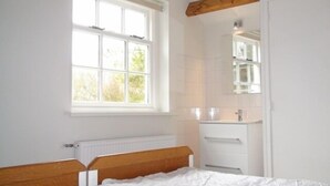 A bedroom with a wooden bed, a window, a white radiator, and a white wardrobe.