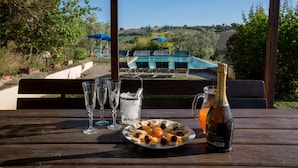 Un tavolo in legno con una bottiglia di champagne, un piatto di frutta e due bicchieri d'acqua.