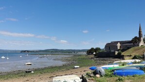 Un paysage côtier avec des bateaux sur la plage, une église et une vue sur la mer.