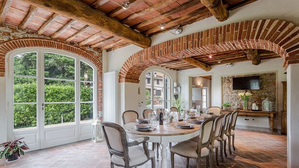 A dining area with a brick fireplace, large arched windows, and a stone wall. - A Romantic Farmhouse with Pool in 10 mins walk away from the Walls of Lucca (Monte San quirico)