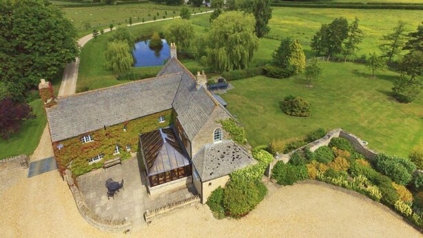 An aerial view of a country house with a pond, surrounded by lush greenery and a clear sky. - The Cotswold Manor Hall, Exclusive Hot Tub, Games Barn, 70 acres of Parkland (Bampton)