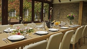 A dining area with a long table set for a meal, surrounded by chairs. - The Cotswold Manor Hall, Exclusive Hot Tub, Games Barn, 70 acres of Parkland (Bampton)