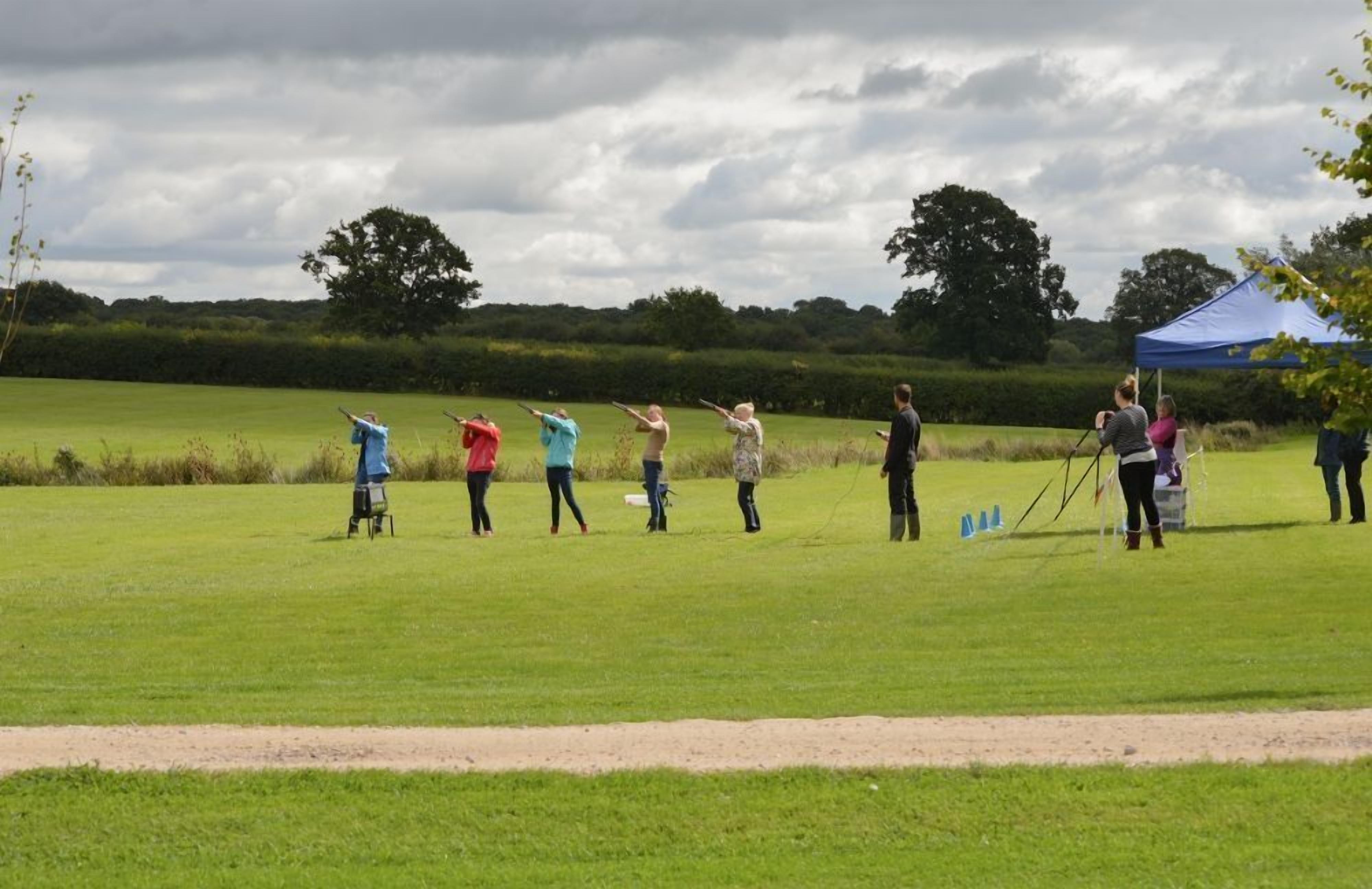 A group of people in a grassy field with a tent in the background.